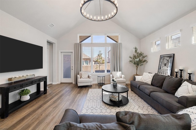 living room with wood-type flooring, a chandelier, and vaulted ceiling