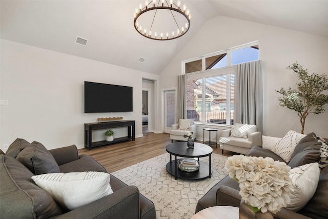 living room with vaulted ceiling, an inviting chandelier, and wood-type flooring