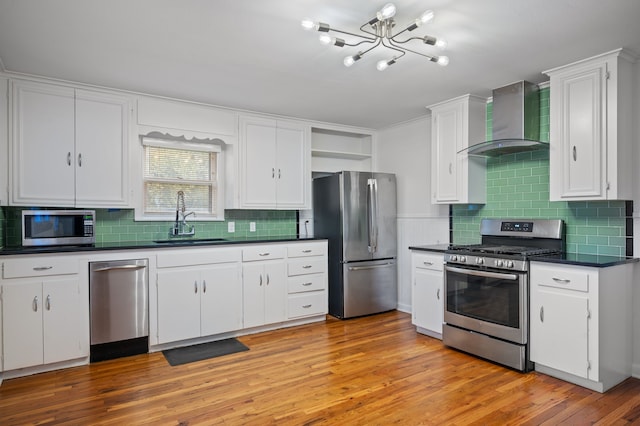 kitchen with wall chimney range hood, sink, appliances with stainless steel finishes, light hardwood / wood-style floors, and white cabinets