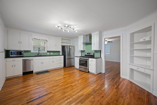 kitchen featuring appliances with stainless steel finishes, white cabinetry, sink, hardwood / wood-style flooring, and wall chimney exhaust hood