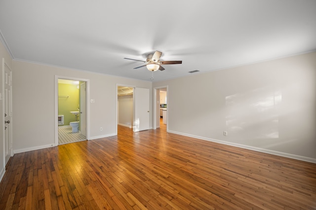 unfurnished bedroom with hardwood / wood-style floors, a spacious closet, ornamental molding, and a closet