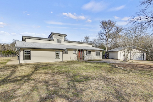 view of front of house featuring a garage, a front lawn, and an outbuilding