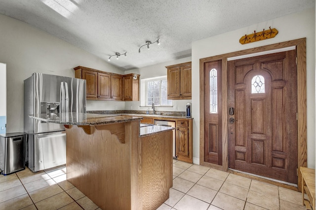 kitchen with vaulted ceiling, a center island, a kitchen bar, appliances with stainless steel finishes, and light tile patterned floors