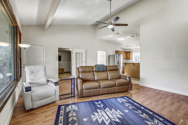 living room featuring ceiling fan, a textured ceiling, light hardwood / wood-style flooring, and lofted ceiling with beams