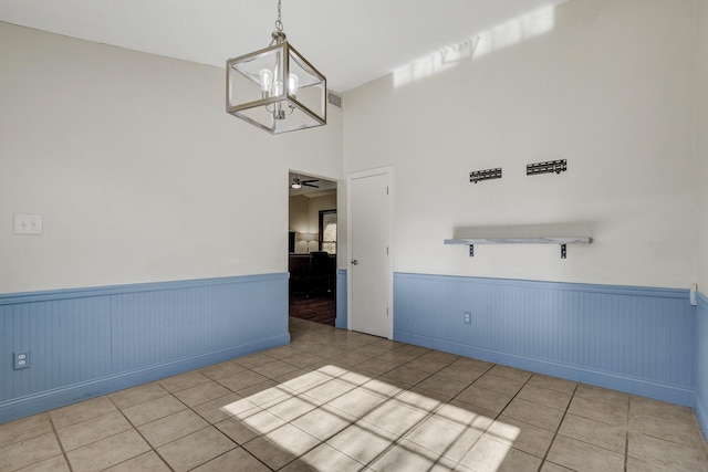 spare room featuring light tile patterned floors and ceiling fan with notable chandelier