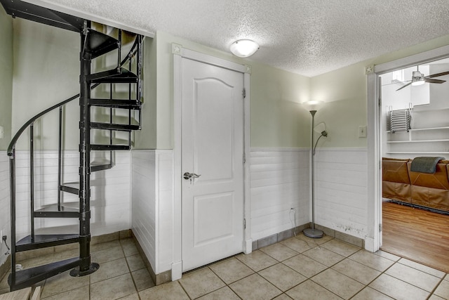 interior space featuring ceiling fan, a textured ceiling, and tile patterned flooring