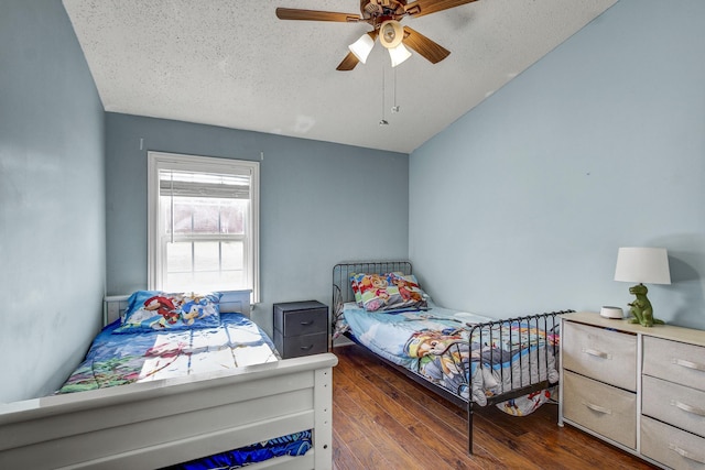 bedroom with ceiling fan, dark wood-type flooring, and a textured ceiling