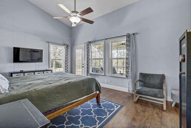 bedroom with ceiling fan, dark hardwood / wood-style flooring, multiple windows, and high vaulted ceiling