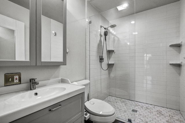 bathroom featuring toilet, vanity, and a tile shower