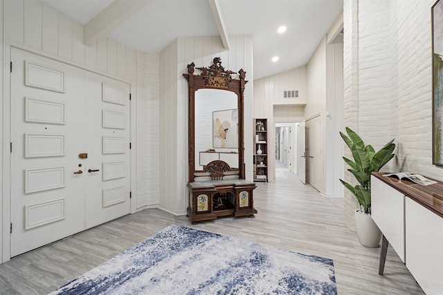 entrance foyer with light hardwood / wood-style flooring, beam ceiling, and wooden walls