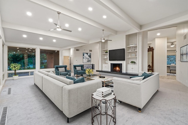 carpeted living room featuring ceiling fan, built in shelves, and beamed ceiling