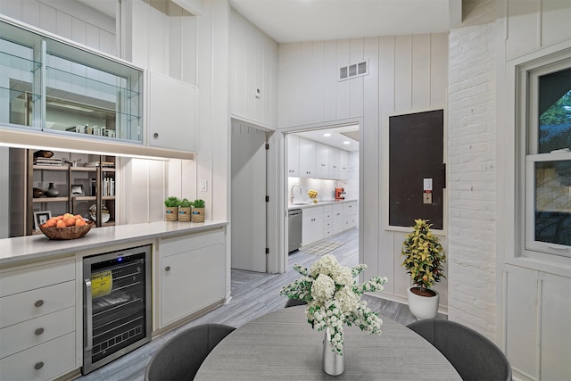 bar with dishwasher, sink, white cabinetry, light hardwood / wood-style flooring, and beverage cooler