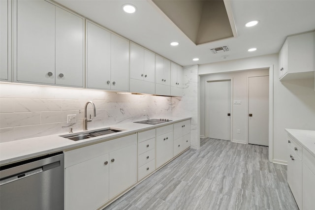 kitchen featuring dishwasher, black electric stovetop, decorative backsplash, sink, and white cabinetry