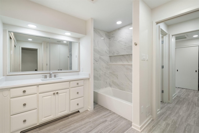 bathroom featuring tiled shower / bath, hardwood / wood-style floors, and vanity