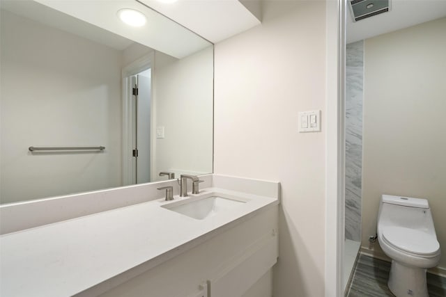 bathroom with toilet, hardwood / wood-style floors, and vanity