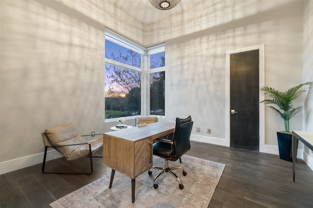 office area with dark wood-type flooring and a towering ceiling