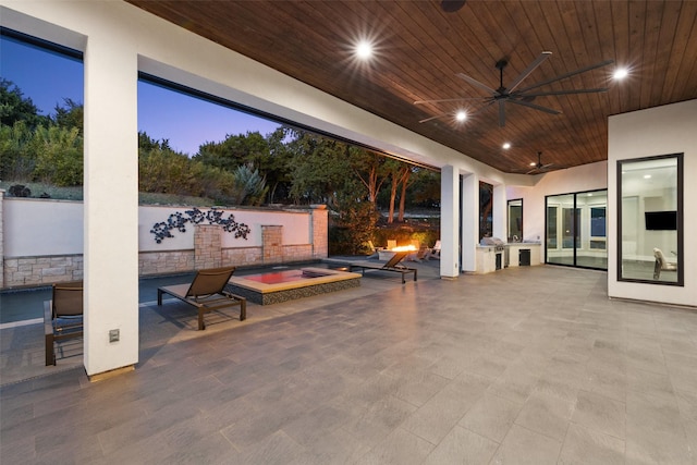 patio terrace at dusk with an in ground hot tub, ceiling fan, and area for grilling