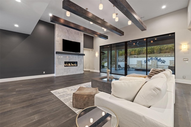 living room with ceiling fan, beamed ceiling, dark hardwood / wood-style floors, and a fireplace