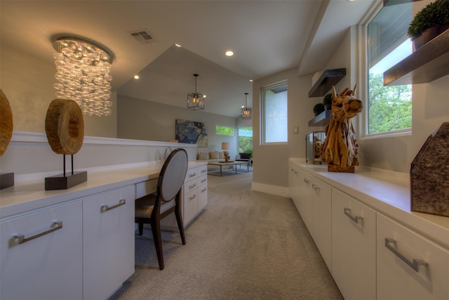 office area featuring light carpet, vaulted ceiling, built in desk, and a chandelier