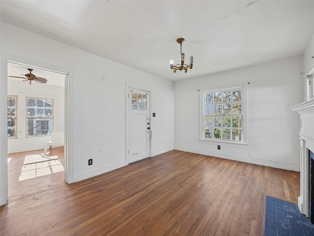 interior space featuring ceiling fan with notable chandelier, hardwood / wood-style floors, and a tiled fireplace