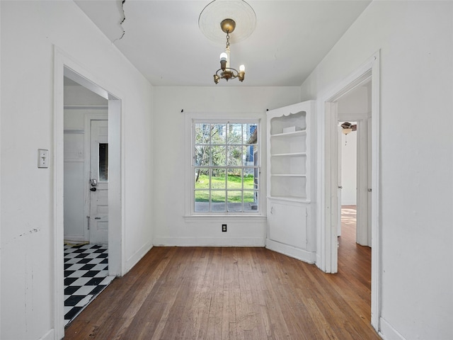 empty room featuring dark hardwood / wood-style flooring and an inviting chandelier