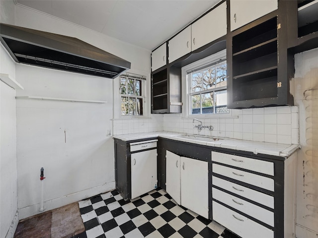 kitchen with sink, a wealth of natural light, white cabinets, and exhaust hood