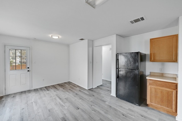 kitchen with black refrigerator and light hardwood / wood-style flooring