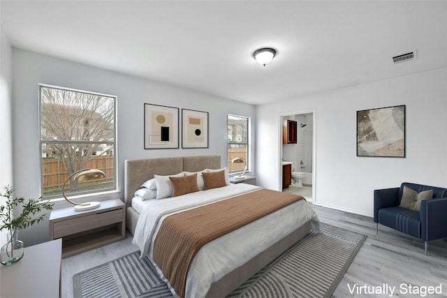 bedroom with connected bathroom and light hardwood / wood-style floors