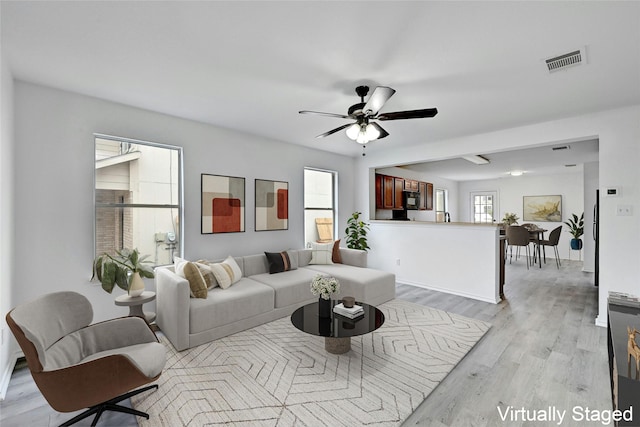 living room with ceiling fan and light hardwood / wood-style flooring