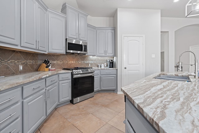 kitchen featuring backsplash, appliances with stainless steel finishes, sink, and gray cabinetry