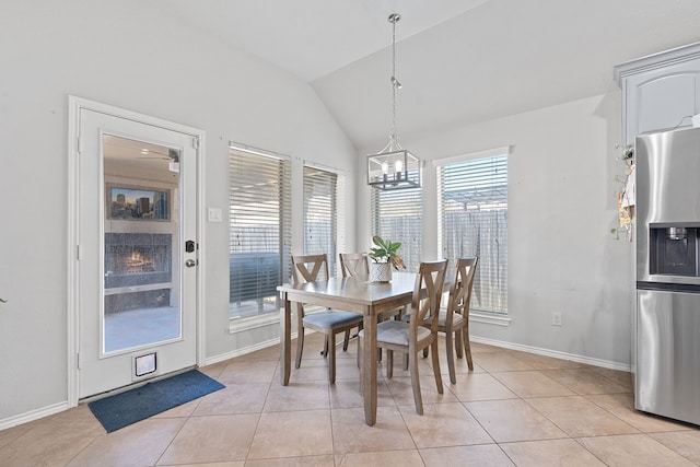 tiled dining space featuring vaulted ceiling and a chandelier