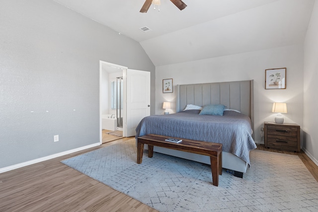 bedroom featuring ceiling fan, light hardwood / wood-style floors, connected bathroom, and vaulted ceiling