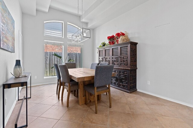 tiled dining area featuring a towering ceiling and a chandelier