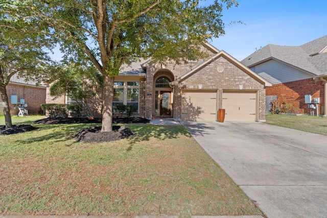 view of front of home featuring a front yard, an attached garage, brick siding, and driveway