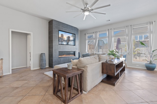 tiled living room featuring ceiling fan and a tile fireplace