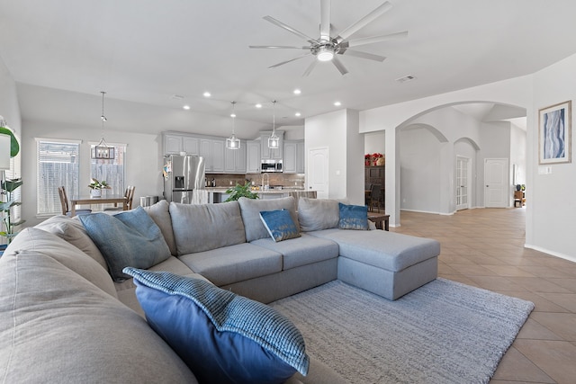 tiled living room featuring ceiling fan with notable chandelier