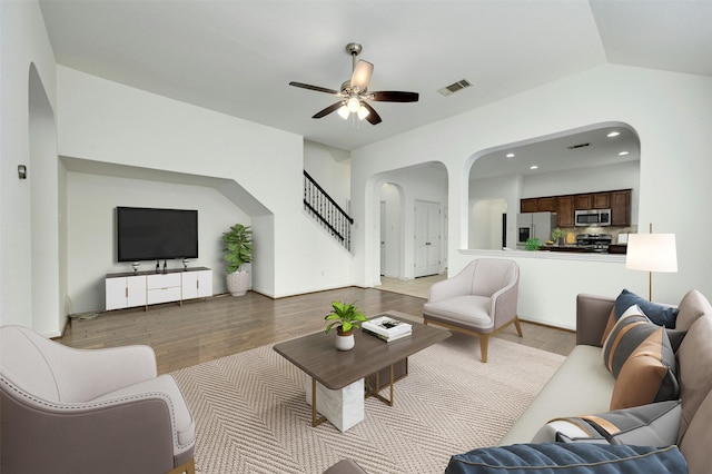 living room with ceiling fan, lofted ceiling, and light wood-type flooring