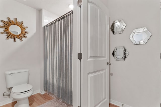 bathroom featuring toilet, wood-type flooring, and a shower with shower curtain