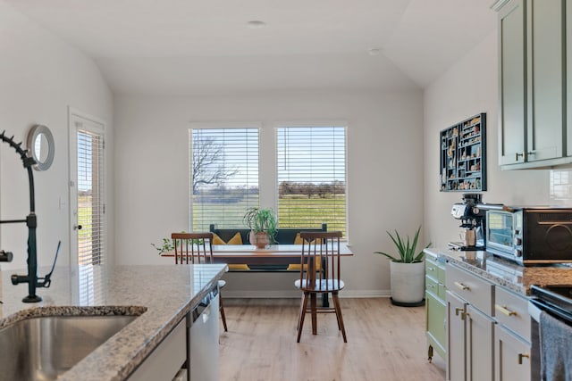 kitchen featuring lofted ceiling, light hardwood / wood-style floors, range with electric cooktop, light stone counters, and stainless steel dishwasher