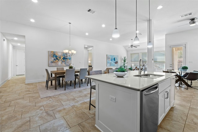 kitchen with sink, decorative light fixtures, white cabinetry, ceiling fan with notable chandelier, and an island with sink