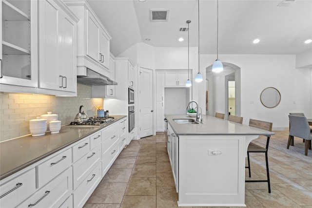 kitchen featuring a kitchen breakfast bar, sink, decorative light fixtures, white cabinets, and a kitchen island with sink