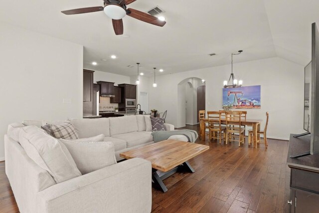 living room with dark hardwood / wood-style flooring, ceiling fan with notable chandelier, and vaulted ceiling