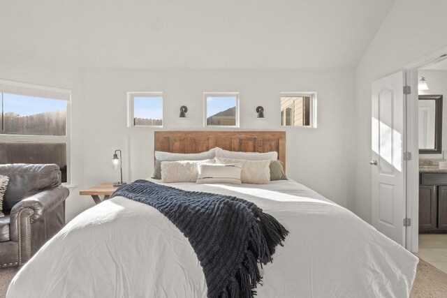 tiled bedroom featuring lofted ceiling and ensuite bathroom