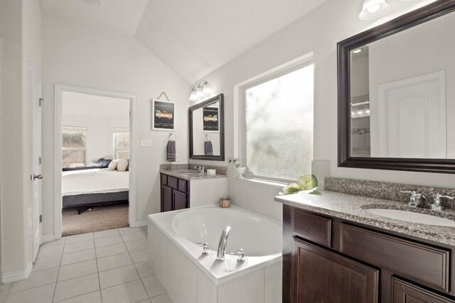 bathroom with tile patterned floors, lofted ceiling, tiled bath, and vanity