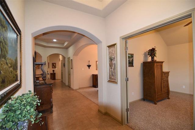 hallway featuring light carpet and a tray ceiling