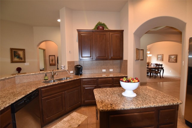 kitchen featuring light stone countertops, sink, light tile patterned floors, and dishwasher