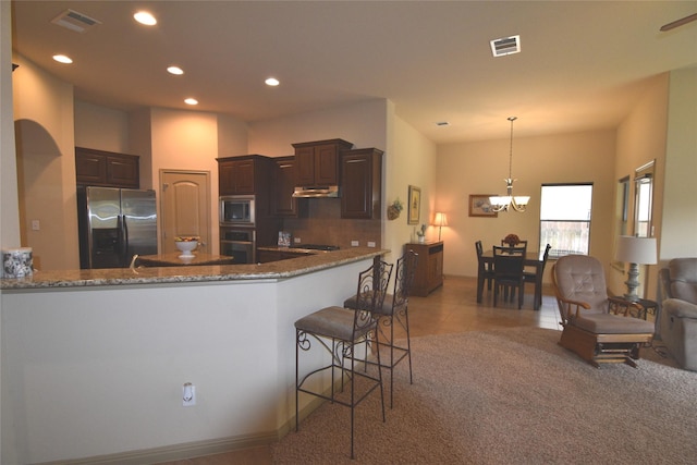 kitchen with dark brown cabinetry, decorative light fixtures, stainless steel appliances, a notable chandelier, and stone counters