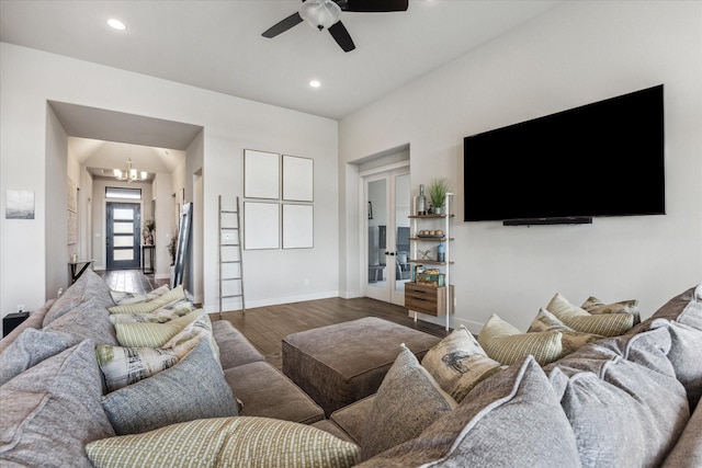 living room featuring dark wood-type flooring, ceiling fan with notable chandelier, and french doors