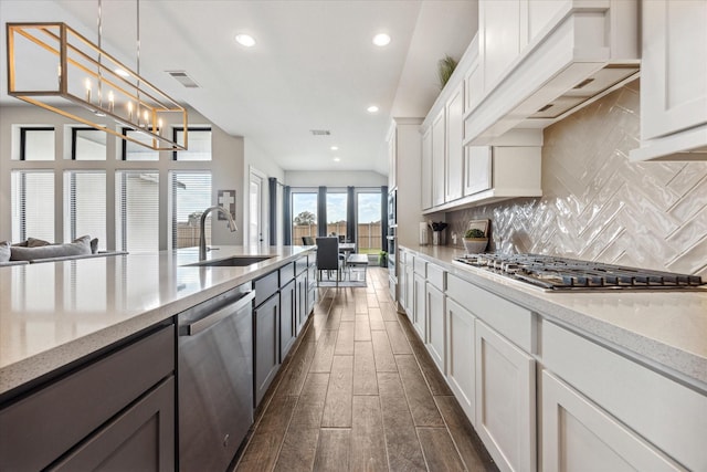 kitchen with custom range hood, stainless steel appliances, white cabinets, and sink