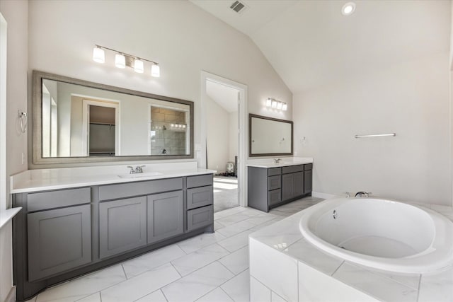 bathroom with lofted ceiling, a relaxing tiled tub, and vanity